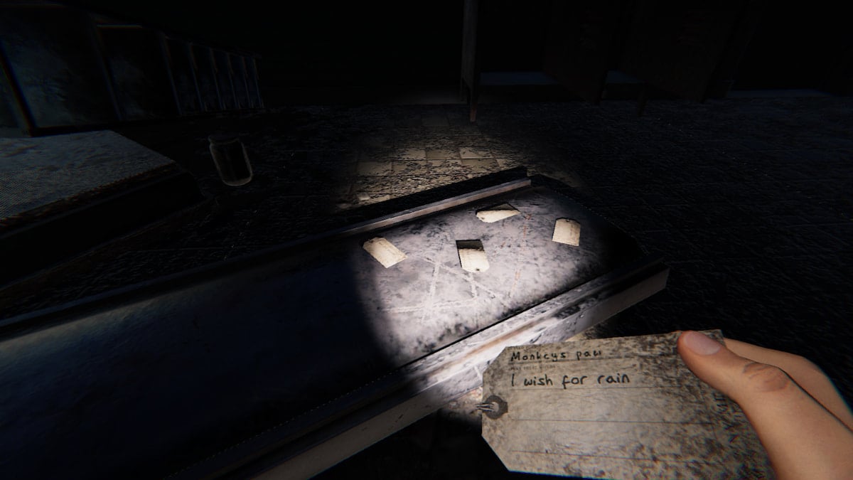 The player holding a Monkey Paw wish that reads "I wish for rain" in front of a pile of four other wishes in Phasmophobia.