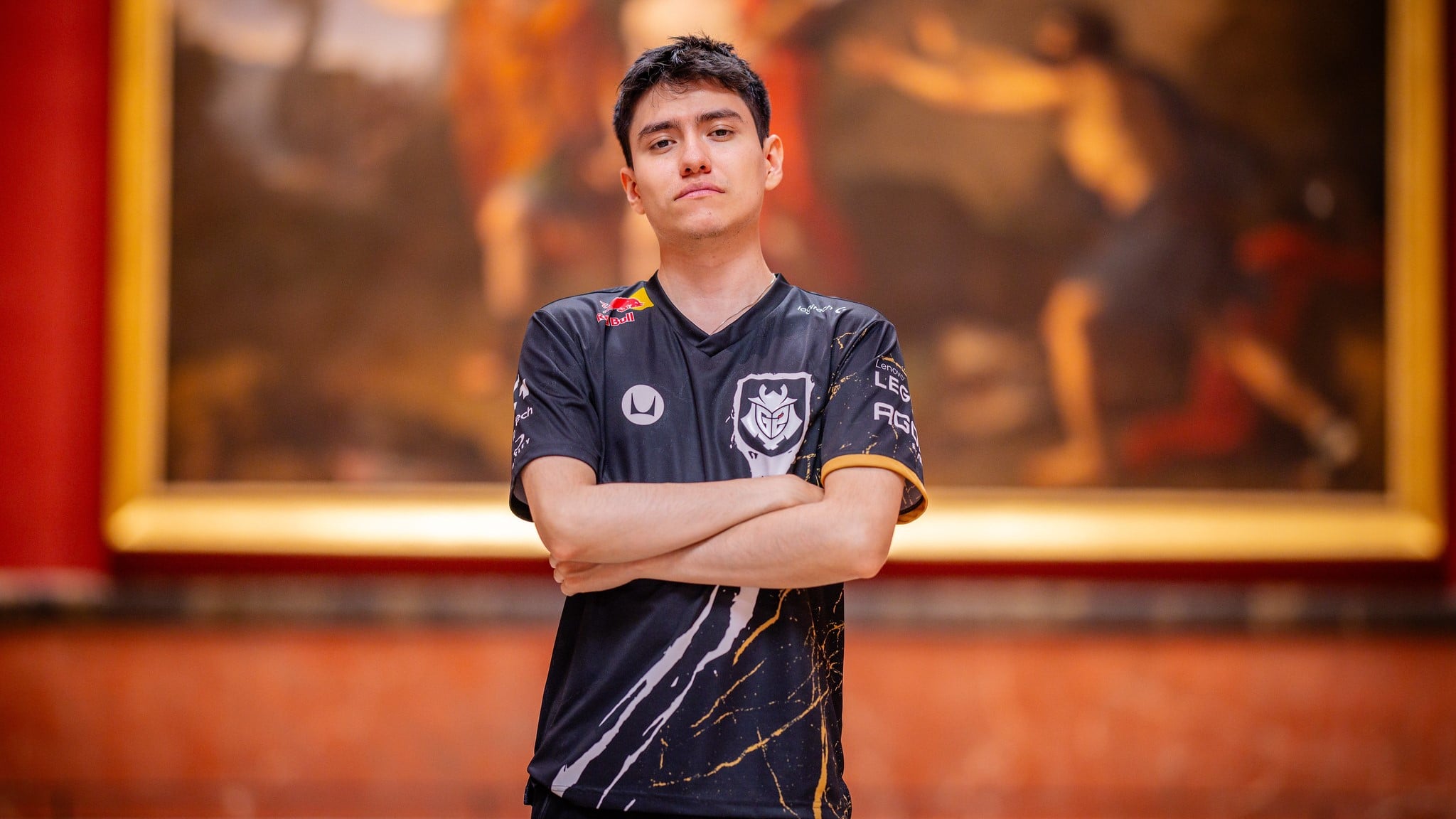 Yike standing in front of a painting and posing for the camera with his arms crossed.