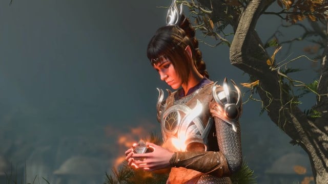 The Cleric Shadowheart holds a small, pointy artifact in her hands next to a tree in BG3.
