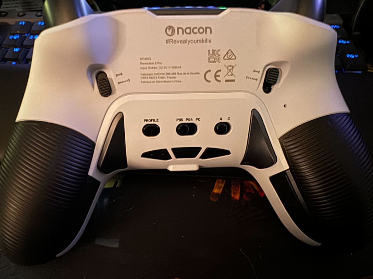 the back of a white controller with black buttons and grips