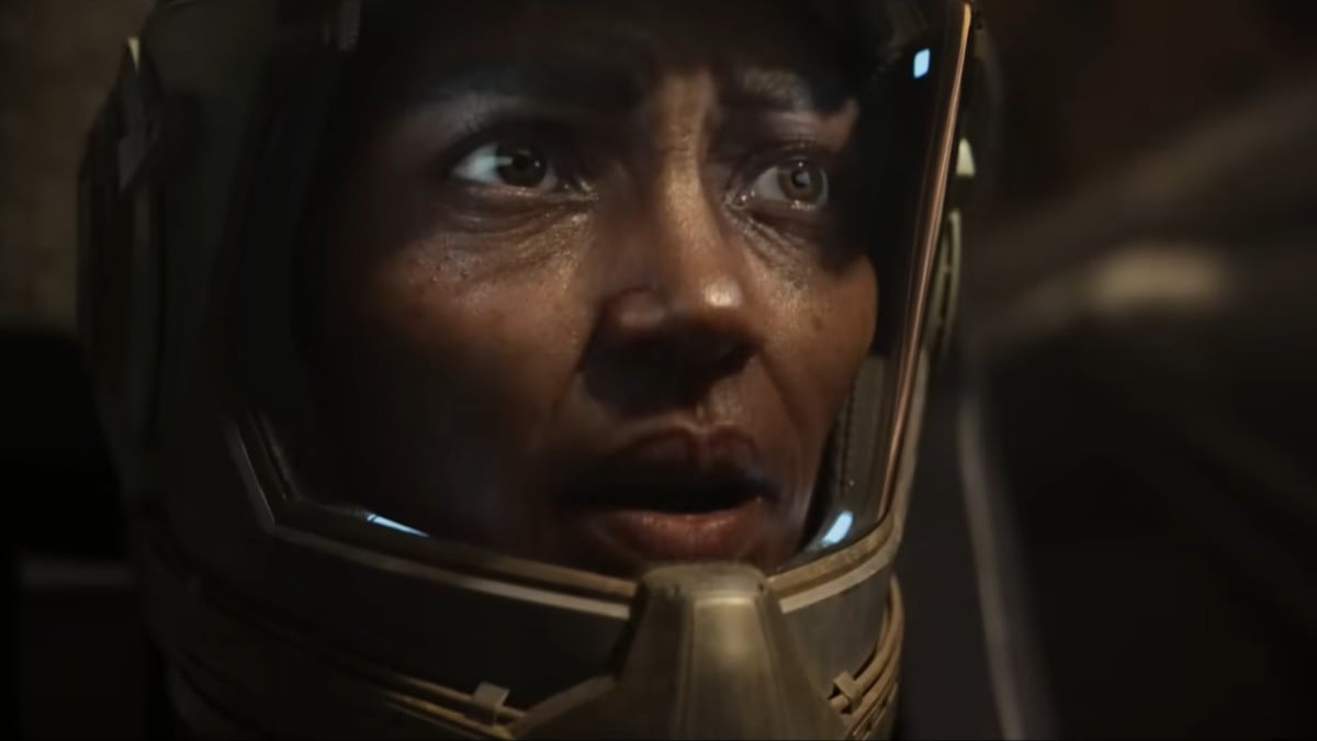 A close up shot of an older Mari, wearing a space helmet