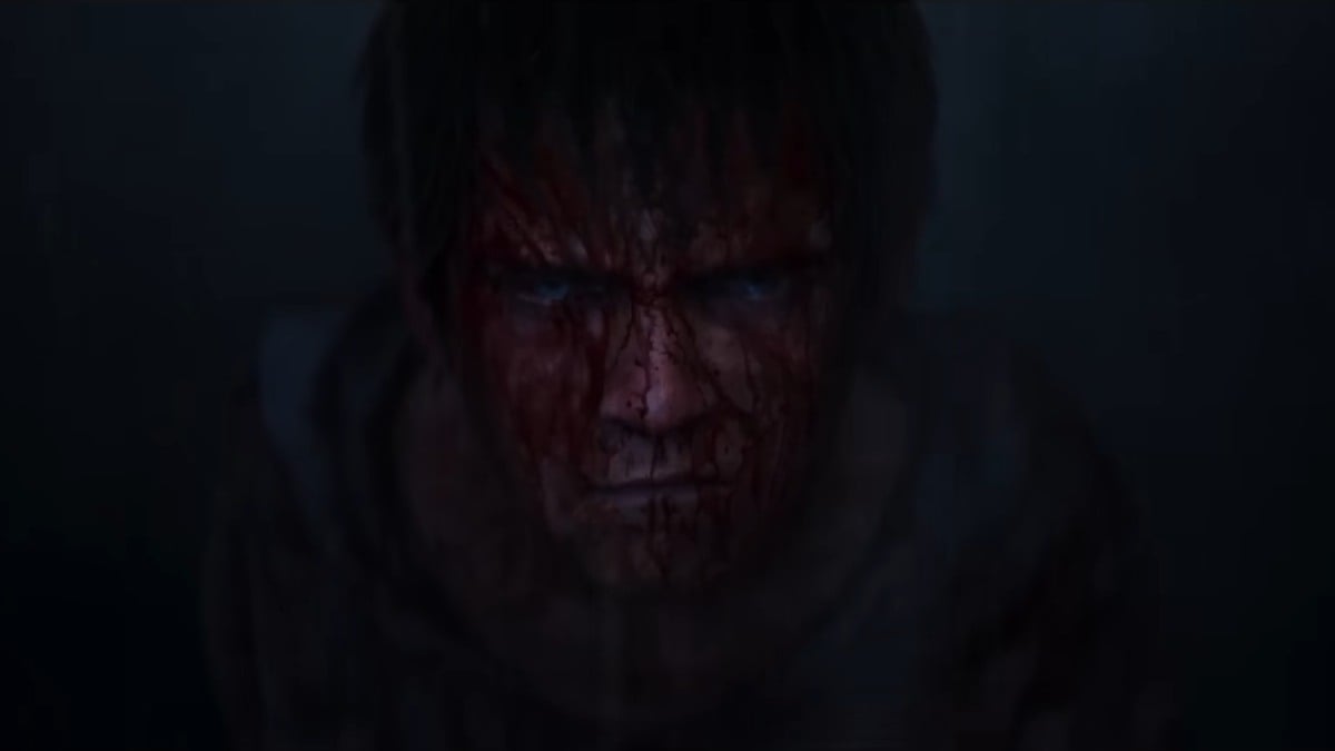 A close up of a young boys blood-covered face looking up at the camera as it rains