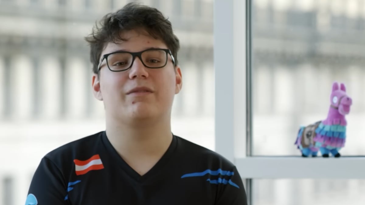 aqua wearing black and sitting on a chair with windows behind him