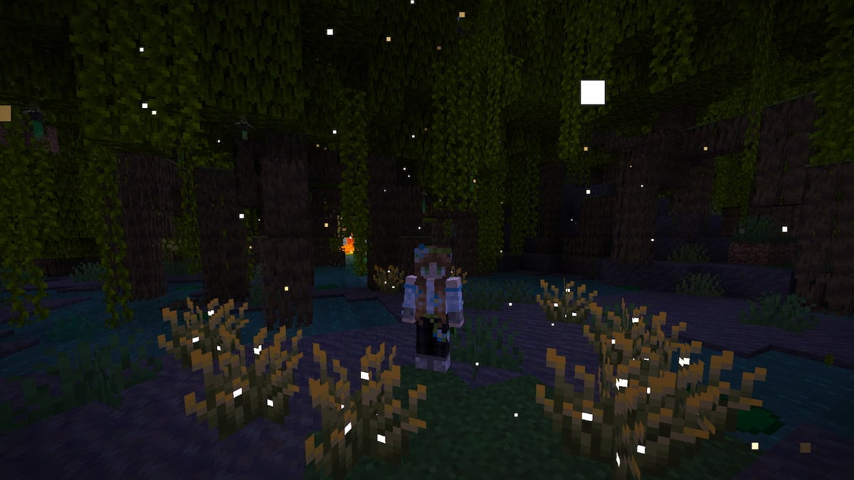A player standing in a mangrove swamp with fireflies flying all around them at night in Minecraft.