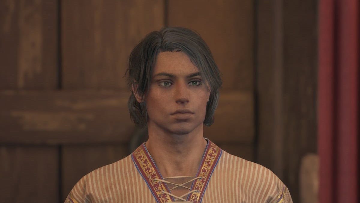 A man in a robe and with shaggy hair looks forward.