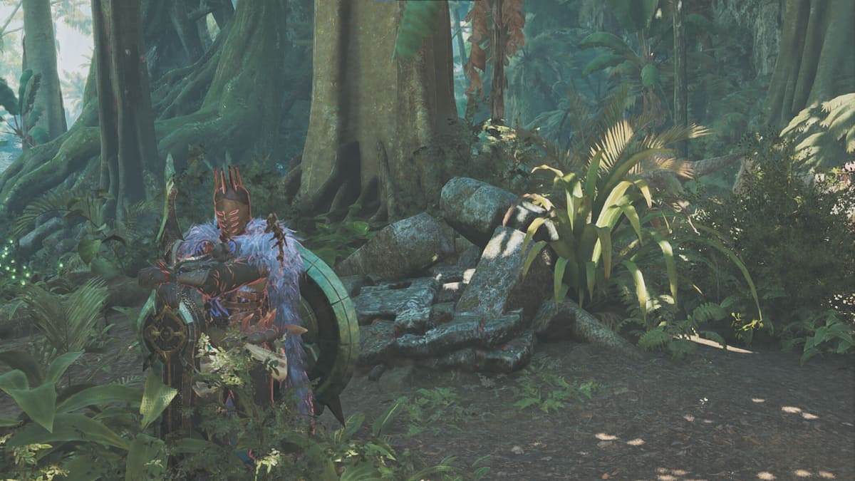 A hunter clad in heavy armor stands next to a giant tree in a jungle.