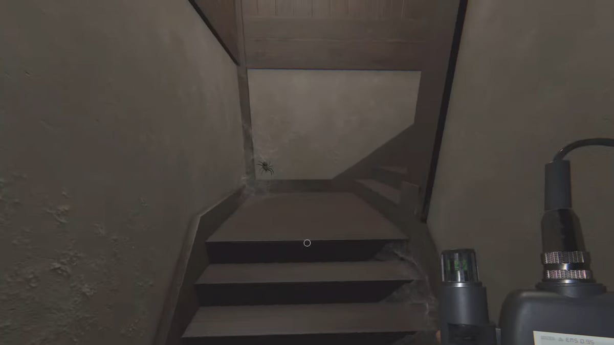 A spider in a web on the stairs leading up to the attic in Phasmophobia.