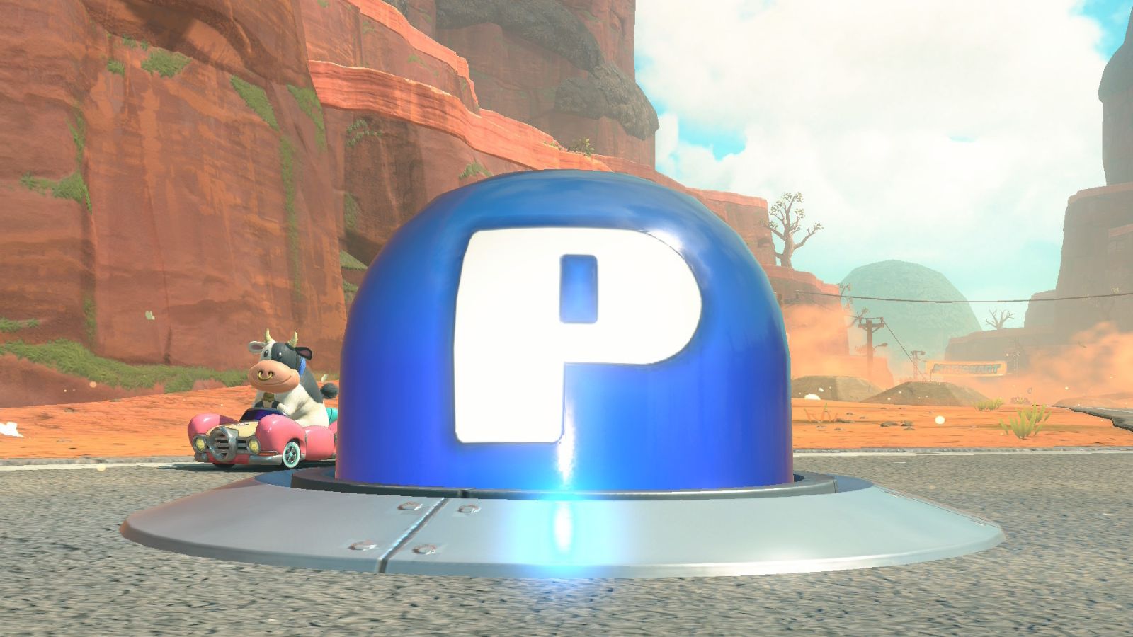 Mario Kart World P Switch with Moo Moo Meadows cow in a pink car in the desert.